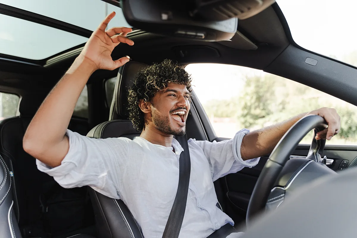 A happy Rinse N' Roll customer cheering in his freshly washed car